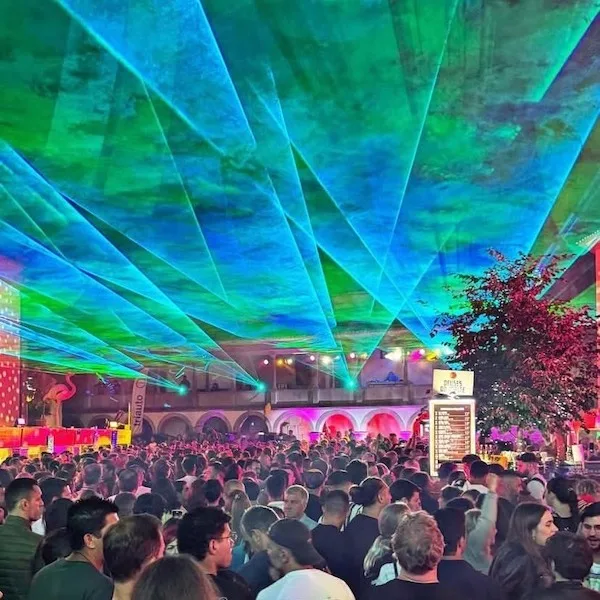 Multidão sob um espetáculo de luzes lasers verdes e azuis, durante um festival noturno