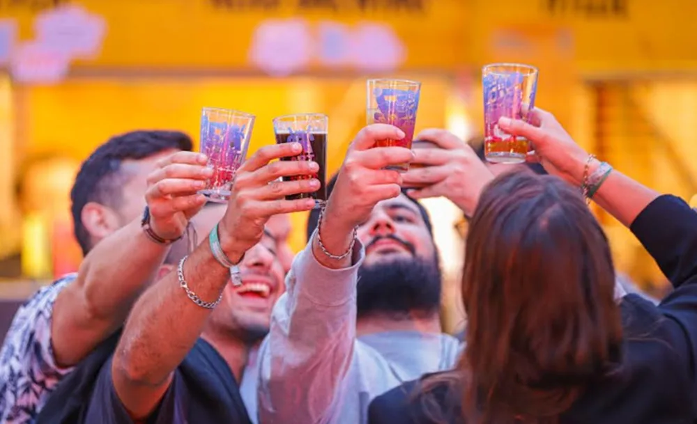 Grupo de amigos brinda com copos de cerveja artesanal num ambiente de festival